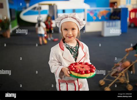 Adorable Preschooler Girl Playing Cook At The Kitchen Or In Restaurant