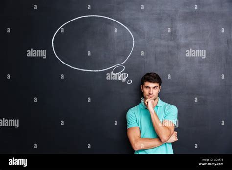 Thoughtful Young Man Standing And Thinking Over Blackboard Background