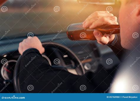 Cerveja Bebendo Do Homem Novo Ao Conduzir Um Carro Foto De Stock