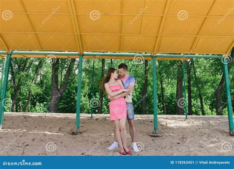 Young Couple Hugging And Smiling At Each Other Under A Canopy On The