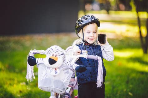 Het Grappige Blonde Van Het Kind Kaukasische Meisje In Een Fietshelm Dichtbij Een Purpere Fiets