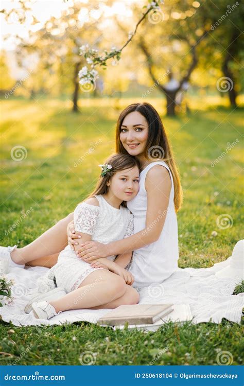 Maman Embrasse Sa Fille Assise Sur Une Couverture Dans Un Jardin Fleuri