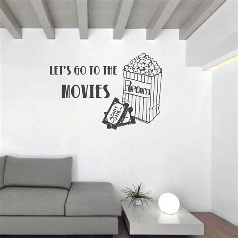 A Living Room With A Couch And Wall Decal That Says Lets Go To The Movies