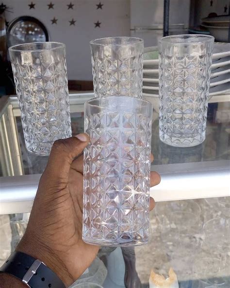 A Hand Holding Three Glasses On Top Of A Glass Shelf In Front Of A Window