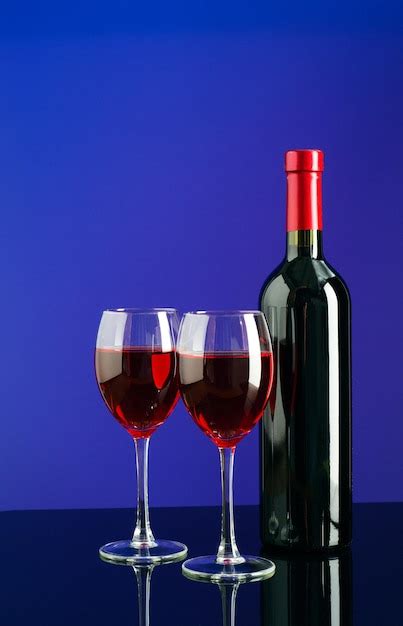 Dois Copos De Vinho Tinto E Uma Garrafa De Vinho No Fundo Azul