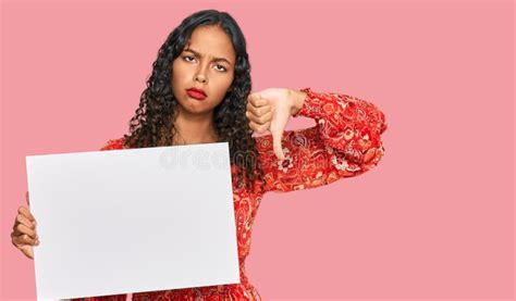 Young African American Girl Holding Blank Empty Banner With Angry Face Negative Sign Showing