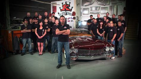 A Group Of People Standing Around A Car