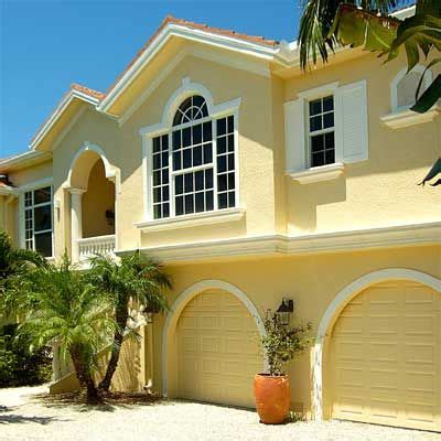 a large yellow house with palm trees in the front yard and two car garages