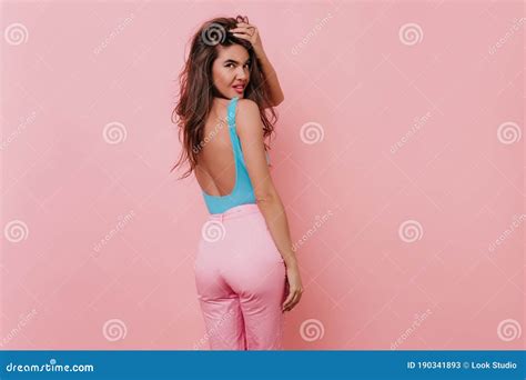 Stunning Tanned Woman In Pink Pants Looking Over Shoulder With