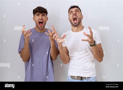 Homosexual Gay Couple Standing Over White Background Crazy And Mad