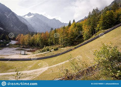 Ski Jump Hill In Front Of A Mountain And Green Autumn Fall Forest In