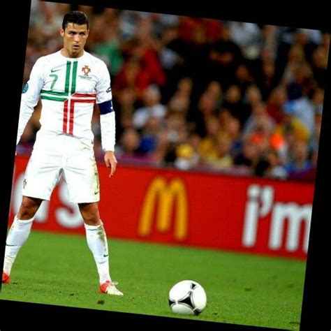 A Man Standing Next To A Soccer Ball On Top Of A Green Field In Front