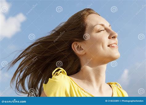 Woman With Eyes Closed Enjoying Sunlight Against Sky Stock Image