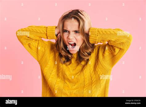 Irritated Beautiful Blonde Girl Screaming While Grabbing Her Head Isolated Over Pink Background