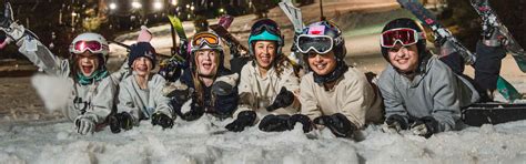 Group of teenage skiers laying on snow in base area.