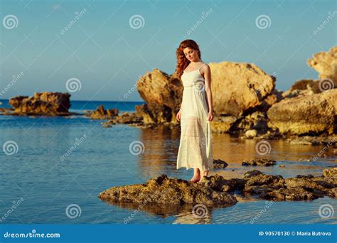 La Fille Sensuelle Rousse Dans Une Robe Blanche Se Tenant Sur La Mer