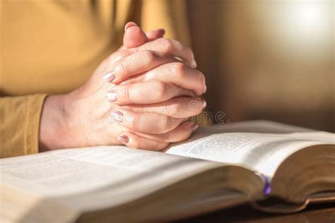 Mujer Que Ruega Con Sus Manos Sobre La Biblia Luz Dura Foto De Archivo