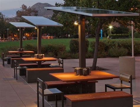 An Outdoor Dining Area With Wooden Tables And Benches At Dusk Along