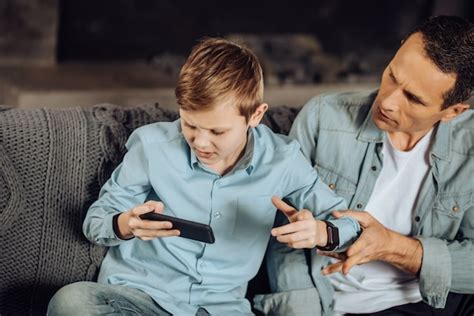 Me D Isto Jovem Pai Irritado Tentando Tirar O Celular Do Filho