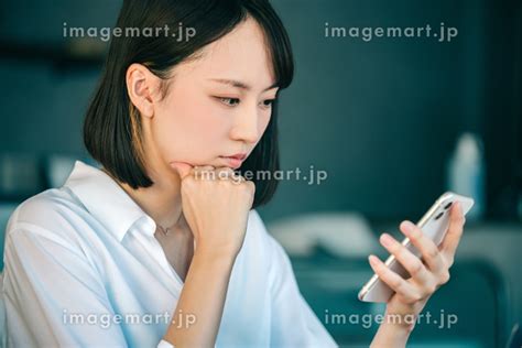 スマホを見て困った顔で考える日本人ビジネスウーマン （女性 人物）の写真素材 227114159 イメージマート