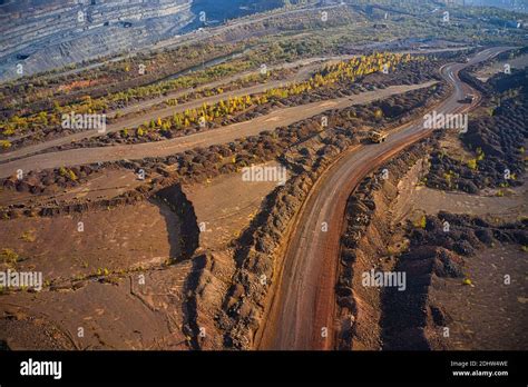 Huge mounds of waste iron ore near the quarry. Belaz trucks driving in ...