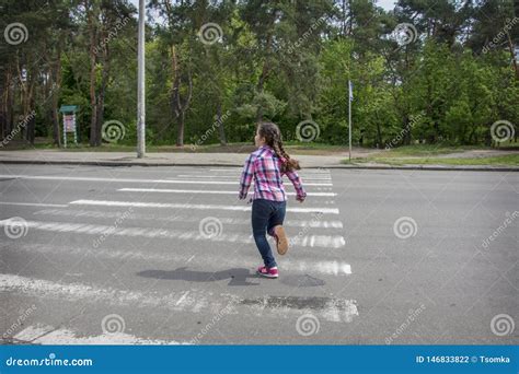 In The Summer On The Street A Little Girl Crosses The Road On A