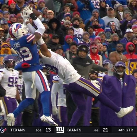 Two Football Players Colliding For The Ball In Front Of A Large Group