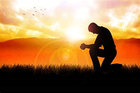 Silhouette Of A Man Kneeling And Praying On Mountain Stock Photos