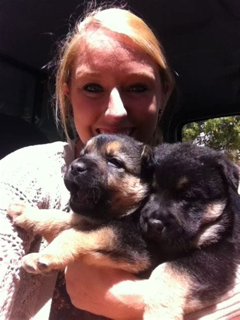 A Woman Holding Two Puppies In Her Arms