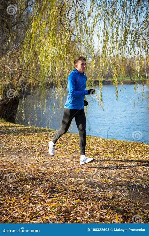 Young Sports Man Running In The Park In Cold Sunny Autumn Morning