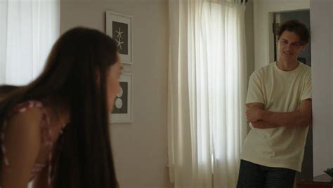 A Man Standing In Front Of A Mirror Next To A Woman With Her Arms Crossed