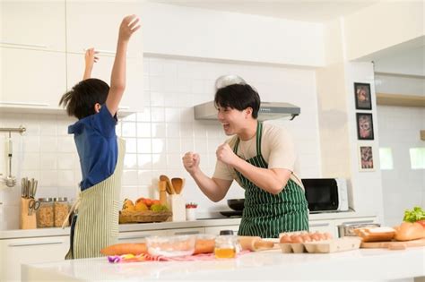 Feliz Joven Asi Tico Padre E Hijo Cocinando En La Cocina En Casa Foto