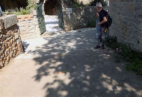 A Man Standing On The Side Of A Road Next To A Stone Wall And Trees