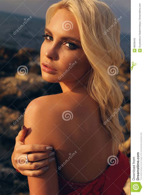 Mooi Meisje Met Blond Haar In Bikini Het Stellen Bij Zonsondergangstrand Stock Afbeelding