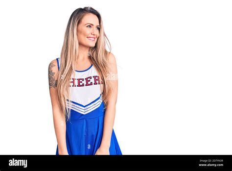 Young Beautiful Blonde Woman Wearing Cheerleader Uniform Looking Away