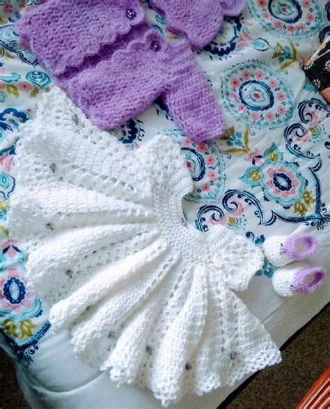 Crocheted Baby Clothes Laid Out On A Bed