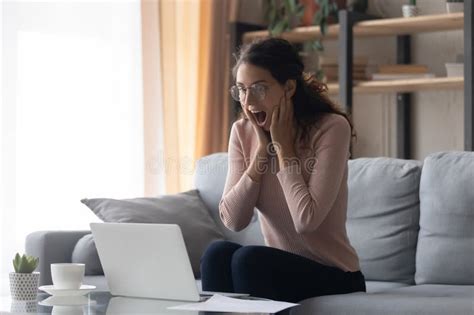 Surprised Excited Woman Wearing Glasses Looking At Laptop Screen Stock