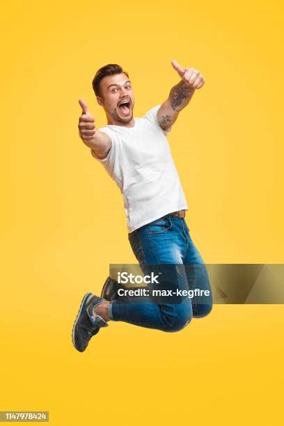 Excited Man Jumping And Gesturing Thumb Up Stock Photo Download Image