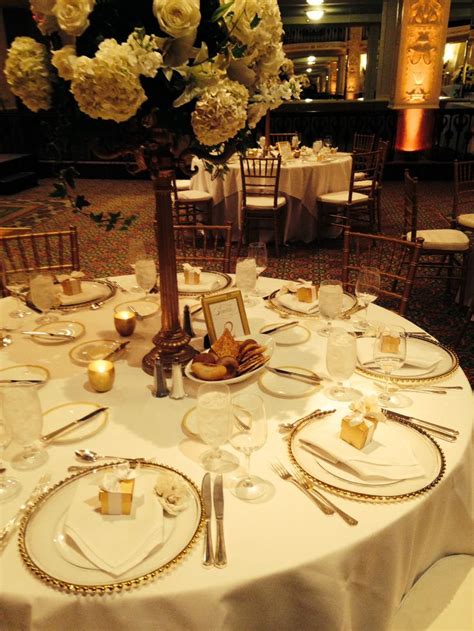 The Table Is Set With White Linens And Gold Place Settings For Dinner