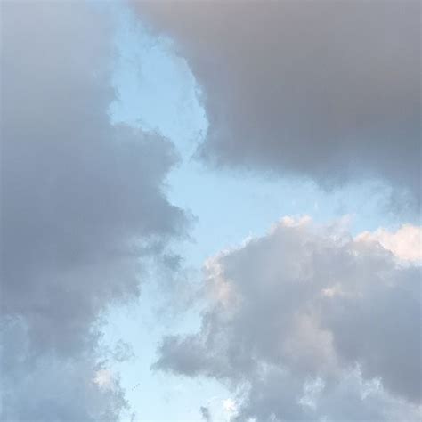 An Airplane Is Flying High In The Sky With Clouds Behind It On A Cloudy Day