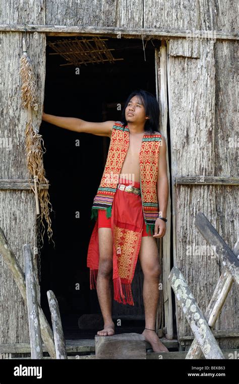 Young Man Of The Iban Tribe Standing In The Doorway Of A Longhouse Near