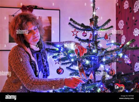 Mature Middle Aged Woman Decorates Her Christmas Tree At Home UK Stock