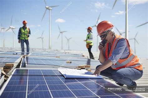 Engineer With Walkie Talkie And Blueprint At Solar Panel At Sunny Power