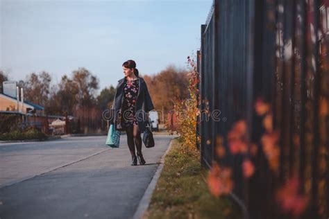Het Gelukkige Brunette In Een Kledingslaag En Gaat Winkelend Onderaan De Straat Stock Foto
