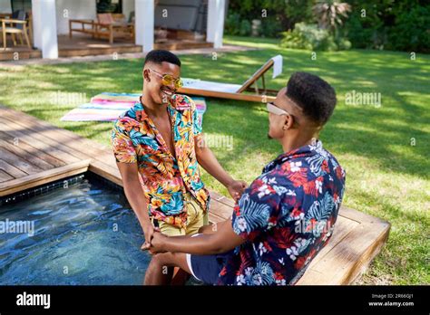 Happy Gay Male Couple Holding Hands In Backyard Swimming Pool Stock Photo Alamy