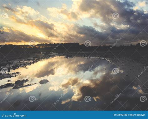 Reflections In A Puddle Of A Beautiful Dramatic Sunset Over A Field