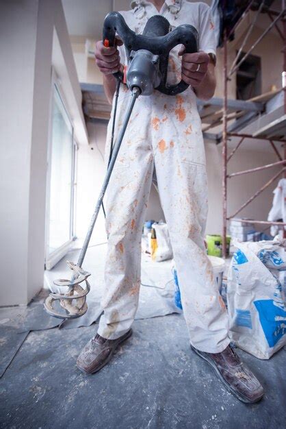 Premium Photo Professional Male Builder Mixing Plaster In Bucket