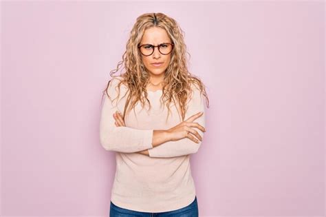 Jeune belle femme blonde portant un pull décontracté et des lunettes sur fond rose expression