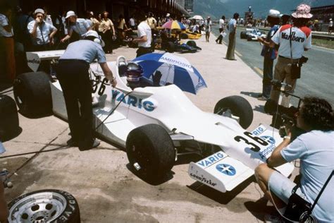 A Group Of People Standing Around A Race Car