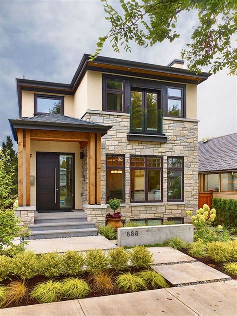 A Modern House With Two Story Windows And Stone Steps Leading Up To The